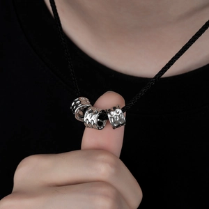 Detail of three hammered silver cylinder beads on a black woven cord necklace cord