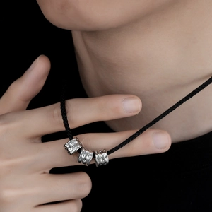 Minimalist silver cylinder pendant necklace with black woven rope on a model