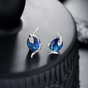 Boucles d'oreilles serpent argentées avec pierre bleue foncée sur présentoir noir mat