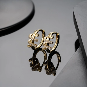 Boucles d'oreilles serpent dorées élégantes avec oxydes de zirconium sur surface noire réfléchissante