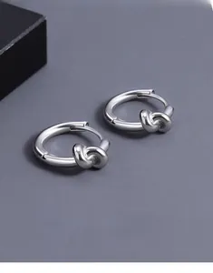 Détail macro de boucles d'oreilles nœud en argent poli sur une surface texturée sombre