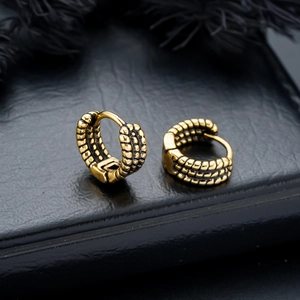 Close-up of golden vintage textured hoop earrings with retro rope pattern on black feathers