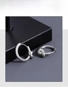 Gros plan de boucles d'oreilles nœud argentées sur un support de bijoux noir