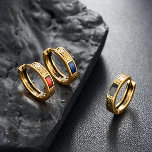 Detailed shot of gold hoop earrings with embossed texture and red, blue, black enamel