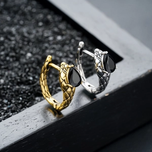 Dettagli di orecchini a cerchio a serpente con trama a squame e pietre nere a goccia