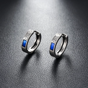 Detail of silver hoop earrings with vintage engraved textures and blue enamel inlays