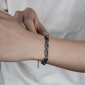 Vue détaillée du bracelet gourmette en acier inoxydable argenté avec détails noirs au poignet