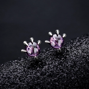 Macro shot of silver cat claw earrings featuring round purple amethyst crystal stones