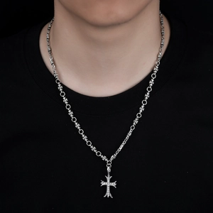 Macro detail of silver cross necklace featuring cubic zirconia pavé and engraved link chain