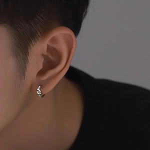 Boucles d'oreilles créoles à nœud argenté minimaliste portées sur le profil de l'oreille