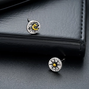 Close-up of vintage celestial sun and moon stud earrings with retro black and gold details