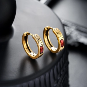 Detail of vintage gold earrings with red enamel inlay and intricate ethnic engravings