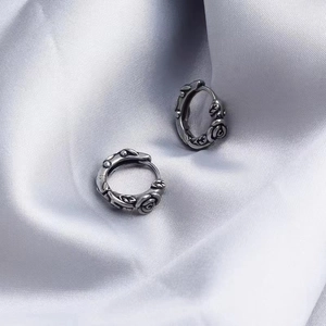 Vintage silver rose hoop earrings featuring detailed floral engravings on a satin background
