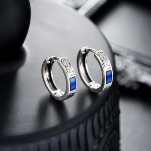 Macro shot of silver ear hoop with vintage relief and rectangular blue gemstone
