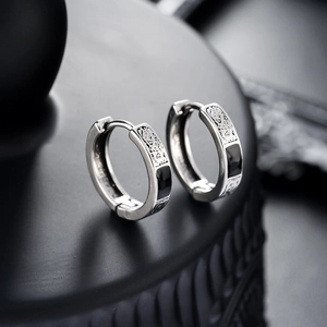 Detailed macro view of vintage silver huggie earrings with black enamel inlay pattern