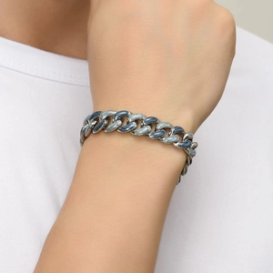 Gros plan d'un bracelet gourmette en émail bleu étoilé sur un poignet d'homme en t-shirt blanc