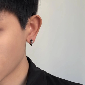 Detail of vintage silver hoop earring with rose relief pattern worn by male model