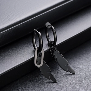 Gros plan de boucles d'oreilles plumes noires mates avec anneaux sur cuir texturé