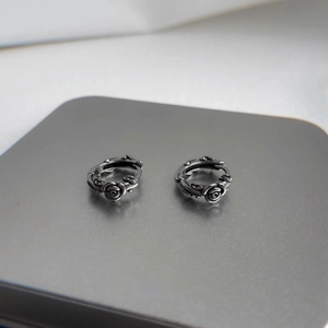 Detailed close-up of retro silver rose earrings with a vintage oxidized metal texture