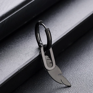 Détail macro du pendentif plume en acier inoxydable noir et anneau d'oreille poli
