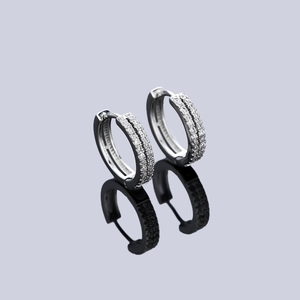 Gros plan sur des boucles d'oreilles en argent serties de deux rangées de zircons et reflet