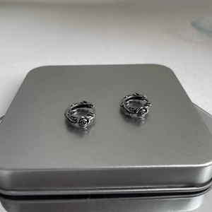 Detail of vintage silver rose earrings with gothic carved petals on metallic surface