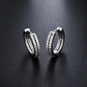 Boucles d'oreilles créoles argentées à double rangée de cristaux sur fond noir texturé