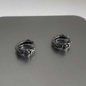 Detailed view of vintage silver rose earrings with embossed floral and vine textures