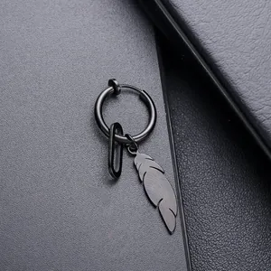 Détail macro du pendentif plume en métal noir sur une boucle d'oreille créole élégante