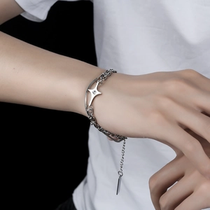Double-layered silver star bracelet with sparkling central diamond on a model's wrist