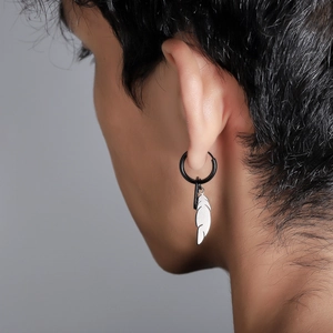 Gros plan d'une boucle d'oreille noire avec pendentif plume argentée sur un mannequin