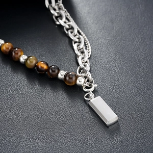Detail of tiger eye beads and silver chain with polished rectangular pendant on leather
