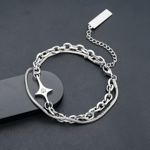Detail of double-layer chain bracelet featuring a polished cross star pendant and lobster clasp