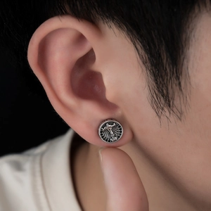 Close-up of vintage magnetic ear clip with embossed cross pattern on model ear