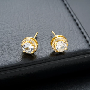 Macro shot of gold halo stud earrings with round brilliant stones on black leather