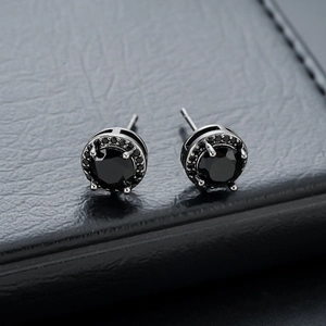Macro shot of black halo stud earrings featuring round cut black stones on dark leather