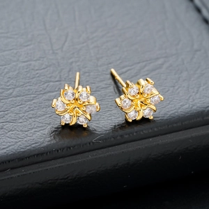 Vue macro de boucles d'oreilles fleurs en zircon sur texture cuir noir élégante