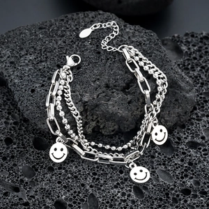 Detail of silver triple-layered chain bracelet with smiling face pendants on black rock