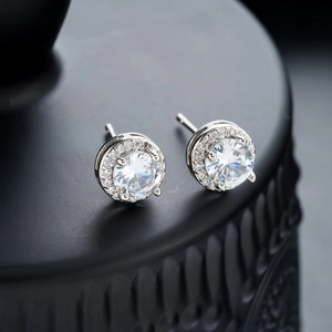 Close-up of sparkling halo stud earrings with micro-pave diamonds on black background