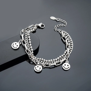 Detail of triple-layer silver stainless steel chain bracelet with smiley face charms