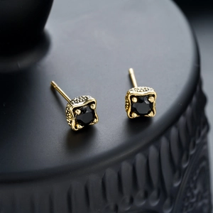 Macro detail of vintage dragon claw square black zircon studs with golden grain texture