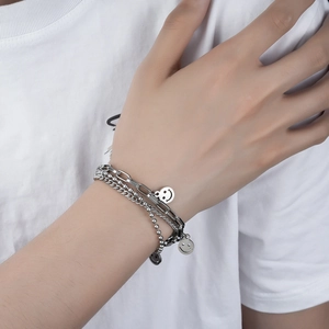Close-up of triple-layered stainless steel bracelet with smiling face charms on model