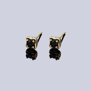 Macro shot of vintage dragon claw stud earrings with square black zircon and relief texture