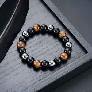 Macro shot of 8mm tiger eye, obsidian, and hematite beads on a dark wooden tray