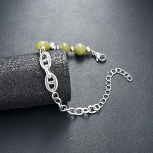 Macro shot of natural green stones with silver pig nose chain link bracelet details