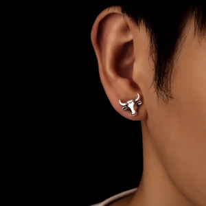 Close-up of vintage silver bull head stud earring worn with dramatic lighting
