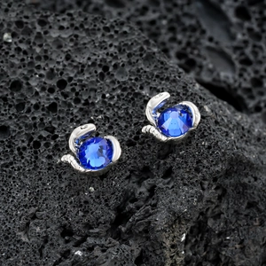 Boucles d'oreilles serpent magnétiques avec cristaux bleus sur roche noire