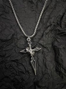 Detailed macro view of a silver dagger cross pendant with ring detail on black texture