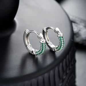 Elegant silver hoop earrings with triple-row green gemstone pavé on black stand