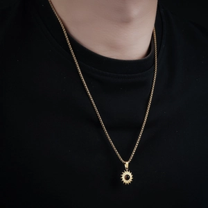 Nahaufnahme einer goldenen Sonnenblumen-Halskette für Herren mit dunkler Perle in der Mitte